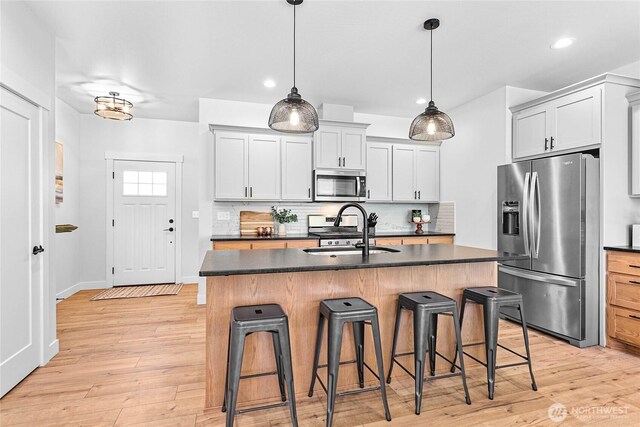2183 Lagerwey Cir, Lynden, WA 98264 - kitchen featuring appliances with stainless steel finishes, dark countertops, decorative backsplash, a breakfast bar, and light wood-style floors
