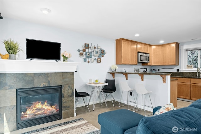 1506 12th Ave S Unit B, Seattle, WA 98144 - kitchen with stainless steel microwave, a breakfast bar area, open floor plan, a tile fireplace, and recessed lighting