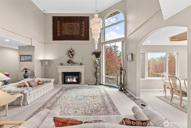 10316 NE 153rd Pl, Bothell, WA 98011 - carpeted living area featuring a towering ceiling, plenty of natural light, arched walkways, a glass covered fireplace, and a chandelier