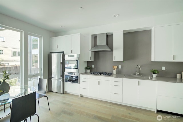 2001 S Norman St Unit B, Seattle, WA 98144 - kitchen featuring wall chimney exhaust hood, appliances with stainless steel finishes, light wood finished floors, modern cabinets, and white cabinetry
