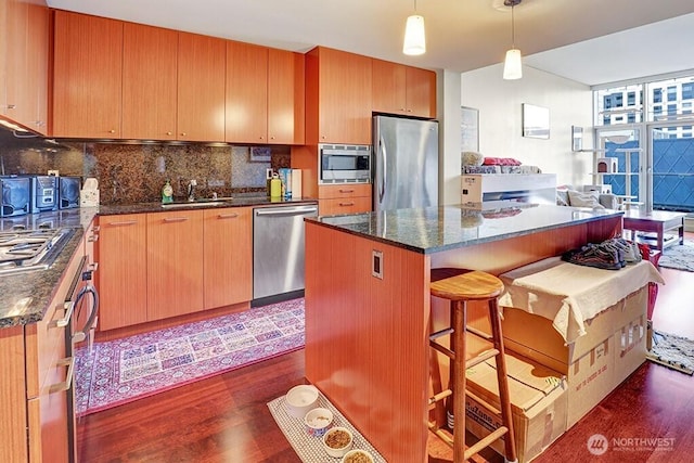 909 5th Ave Unit 1103, Seattle, WA 98164 - kitchen with appliances with stainless steel finishes, dark wood-style flooring, decorative backsplash, and a kitchen island
