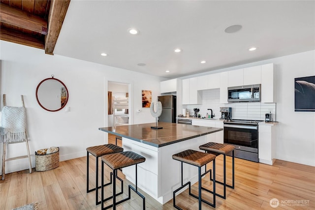 108 E Lake Stevens Rd, Lake Stevens, WA 98258 - kitchen featuring appliances with stainless steel finishes, a breakfast bar, light wood finished floors, white cabinets, and recessed lighting