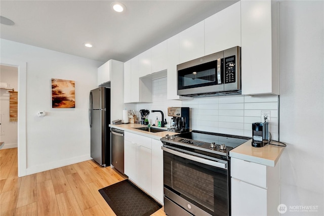 108 E Lake Stevens Rd, Lake Stevens, WA 98258 - kitchen featuring stainless steel appliances, light countertops, white cabinets, light wood finished floors, and recessed lighting