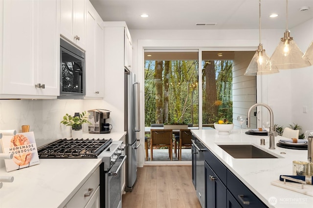 13434 HS3 NE 112th Pl, Redmond, WA 98052 - kitchen with a sink, stainless steel appliances, white cabinetry, light wood finished floors, and decorative light fixtures