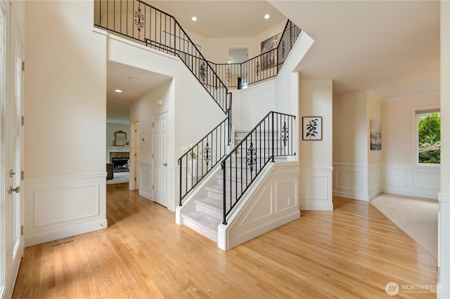 8228 NE 187th Way, Kenmore, WA 98028 - foyer entrance featuring light wood finished floors, a fireplace, a decorative wall, stairs, and a wainscoted wall