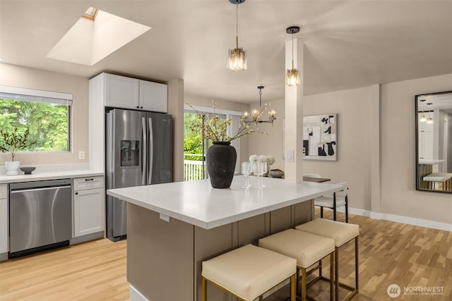 539 129th Ave SE, Bellevue, WA 98005 - kitchen featuring appliances with stainless steel finishes, light wood-style flooring, plenty of natural light, and a breakfast bar area