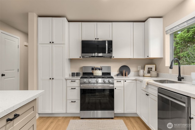 539 129th Ave SE, Bellevue, WA 98005 - kitchen featuring stainless steel appliances, light wood-style flooring, and white cabinetry