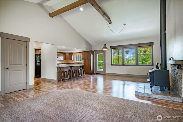 9206 Delta Line Rd, Custer, WA 98240 - living area featuring a wood stove, beamed ceiling, light wood-type flooring, and high vaulted ceiling