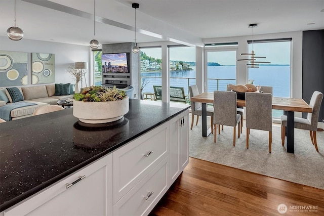 3717 Beach Dr SW Unit 207, Seattle, WA 98116 - kitchen with dark wood finished floors, white cabinetry, decorative light fixtures, open floor plan, and dark stone counters