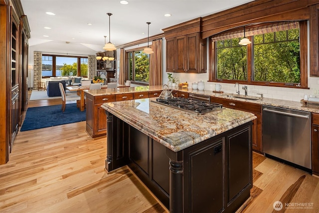 8260 Avalon Dr, Mercer Island, WA 98040 - kitchen featuring appliances with stainless steel finishes, a sink, a kitchen island, light wood-type flooring, and tasteful backsplash