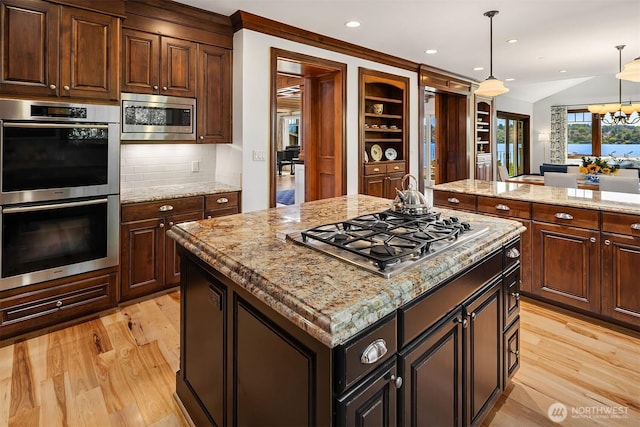 8260 Avalon Dr, Mercer Island, WA 98040 - kitchen with stainless steel appliances, light wood finished floors, a center island, decorative light fixtures, and light stone countertops