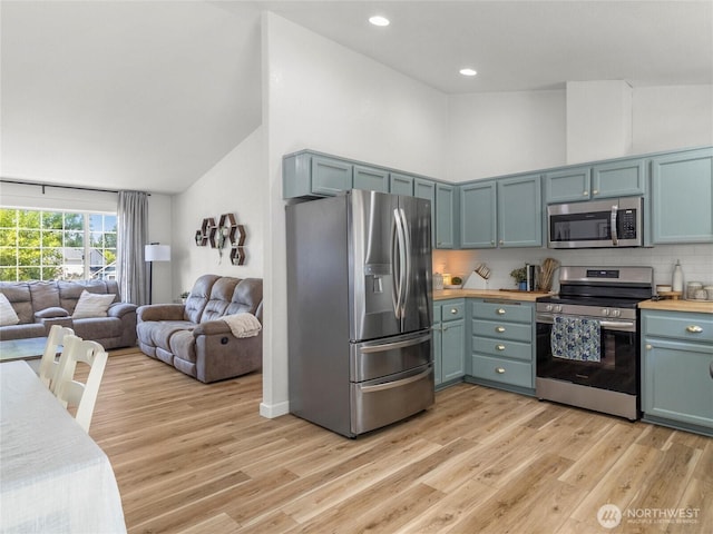 10541 Farwest Ct SE, Yelm, WA 98597 - kitchen featuring appliances with stainless steel finishes, light wood-style flooring, open floor plan, blue cabinetry, and decorative backsplash