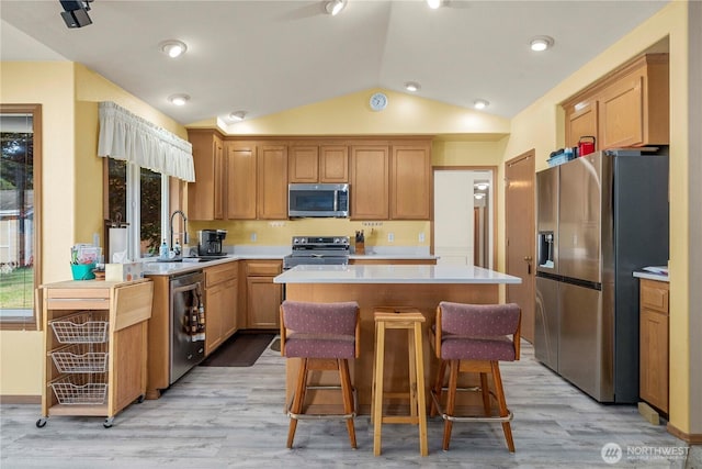 6610 227th Street Ct E, Spanaway, WA 98387 - kitchen featuring stainless steel appliances, vaulted ceiling, light countertops, a center island, and light wood-type flooring