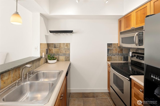 1545 NW 57th St Unit 423, Seattle, WA 98107 - kitchen featuring stainless steel appliances, a sink, tasteful backsplash, brown cabinets, and baseboards