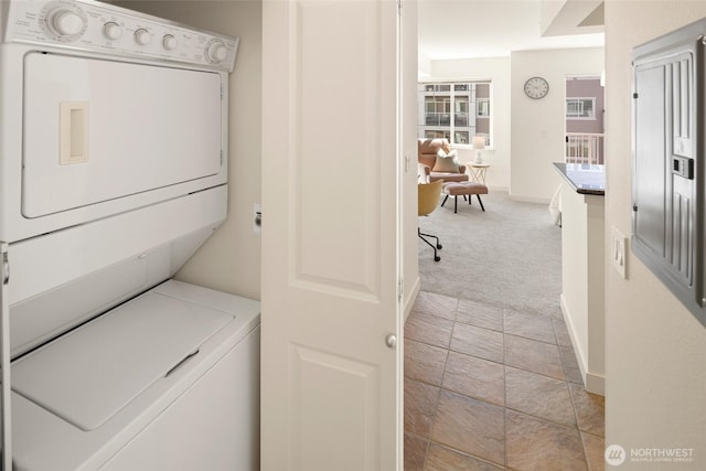 1545 NW 57th St Unit 423, Seattle, WA 98107 - laundry area featuring stacked washer and clothes dryer, light carpet, and baseboards