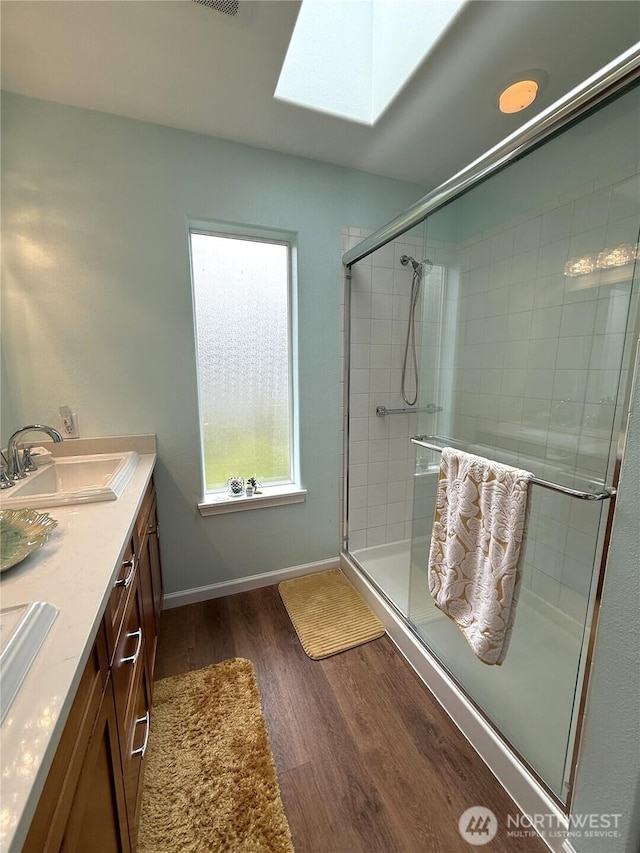 762 Evergreen Ave SE, Ocean Shores, WA 98569 - full bathroom featuring wood finished floors, a skylight, a shower stall, and double vanity