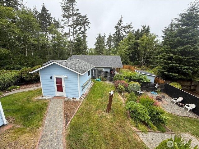 762 Evergreen Ave SE, Ocean Shores, WA 98569 - back of property featuring a fenced backyard, an outdoor structure, and roof with shingles