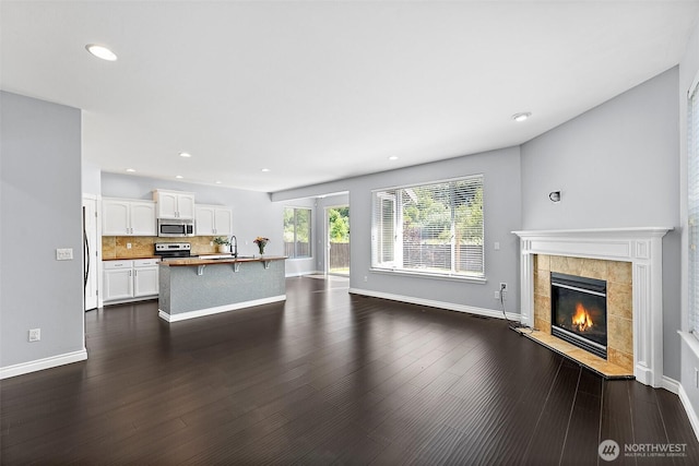 1208 Goldfinch Ave SW, Orting, WA 98360 - unfurnished living room featuring a tiled fireplace, recessed lighting, and dark wood-style flooring