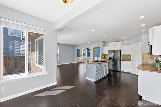 1208 Goldfinch Ave SW, Orting, WA 98360 - kitchen featuring stainless steel appliances, arched walkways, white cabinets, decorative backsplash, and dark wood finished floors