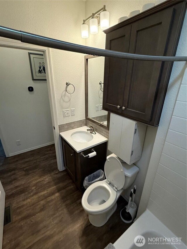 2101 S 324th St Unit 107, Federal Way, WA 98003 - bathroom featuring wood finished floors, toilet, vanity, a textured wall, and a tub to relax in