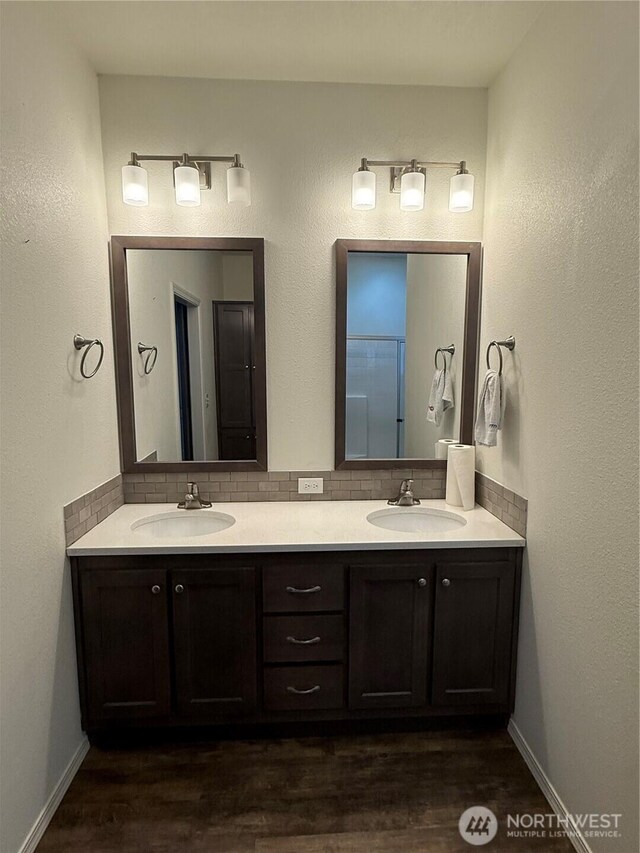 2101 S 324th St Unit 107, Federal Way, WA 98003 - bathroom featuring tasteful backsplash, double vanity, wood finished floors, and baseboards