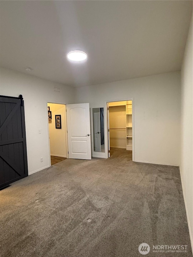 2101 S 324th St Unit 107, Federal Way, WA 98003 - unfurnished bedroom with carpet flooring, baseboards, a spacious closet, and a barn door
