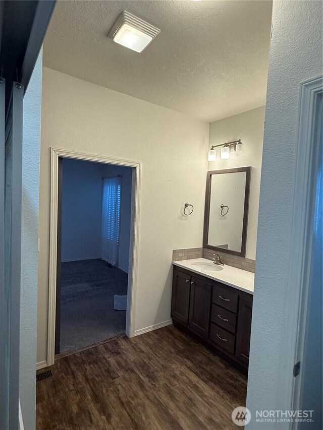 2101 S 324th St Unit 107, Federal Way, WA 98003 - bathroom with wood finished floors, vanity, a textured ceiling, baseboards, and a textured wall