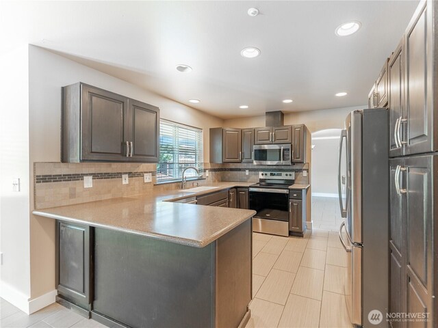 2422 Highland View Dr, East Wenatchee, WA 98802 - kitchen with stainless steel appliances, a sink, arched walkways, backsplash, and a peninsula