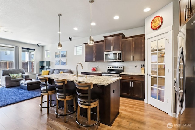 15323 NE 108th Way, Vancouver, WA 98682 - kitchen with appliances with stainless steel finishes, open floor plan, dark brown cabinets, light wood-style floors, and a kitchen bar