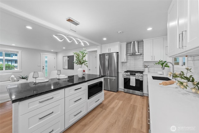 7713 NE 141st St, Kirkland, WA 98034 - kitchen with appliances with stainless steel finishes, wall chimney exhaust hood, light wood finished floors, backsplash, and white cabinets