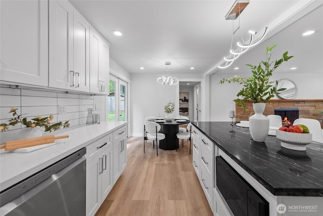 7713 NE 141st St, Kirkland, WA 98034 - kitchen with stainless steel dishwasher, a chandelier, white cabinets, backsplash, and light wood-style flooring