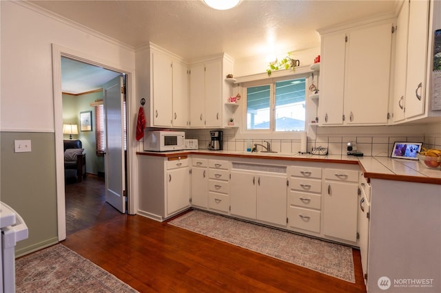 50 Blackberry St, Forks, WA 98331 - kitchen with white microwave, tasteful backsplash, open shelves, dark wood finished floors, and ornamental molding