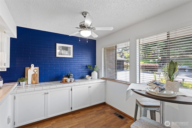10742 Glen Acres Dr S Unit T-27, Seattle, WA 98168 - kitchen with tile countertops, a textured ceiling, white cabinets, ceiling fan, and wood finished floors