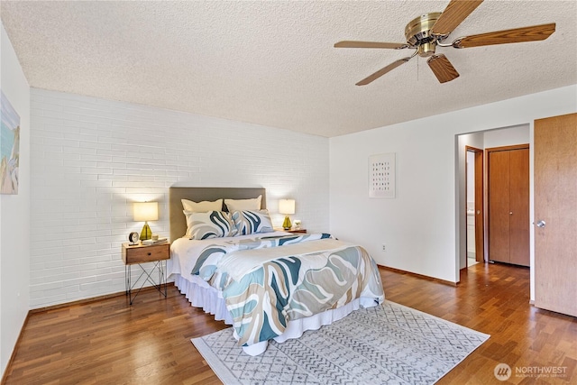 10742 Glen Acres Dr S Unit T-27, Seattle, WA 98168 - bedroom featuring brick wall, wood finished floors, a textured ceiling, and a ceiling fan