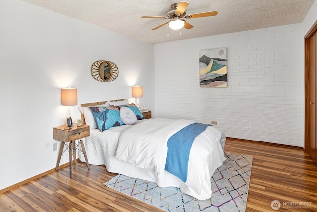 10742 Glen Acres Dr S Unit T-27, Seattle, WA 98168 - bedroom featuring brick wall, wood finished floors, a textured ceiling, and ceiling fan
