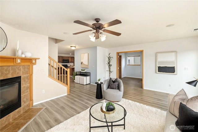 21721 SE 299th Way, Kent, WA 98042 - living room with stairway, wood finished floors, a tiled fireplace, and a ceiling fan