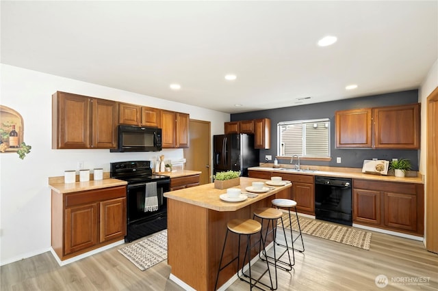 21721 SE 299th Way, Kent, WA 98042 - kitchen with black appliances, light countertops, light wood-type flooring, a kitchen breakfast bar, and a kitchen island