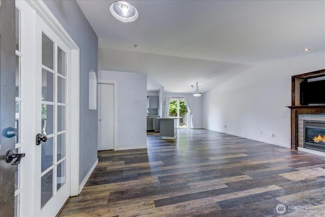 7116 200th Street Ct E, Spanaway, WA 98387 - unfurnished living room featuring dark wood-type flooring, a glass covered fireplace, lofted ceiling, and french doors