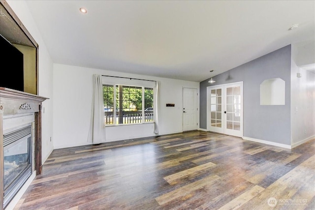 7116 200th Street Ct E, Spanaway, WA 98387 - unfurnished living room with lofted ceiling, wood finished floors, a glass covered fireplace, french doors, and recessed lighting