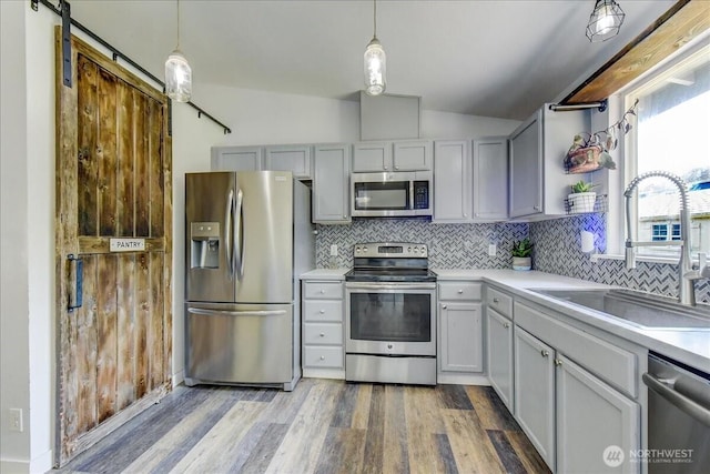 7116 200th Street Ct E, Spanaway, WA 98387 - kitchen featuring stainless steel appliances, vaulted ceiling, decorative backsplash, wood finished floors, and light countertops