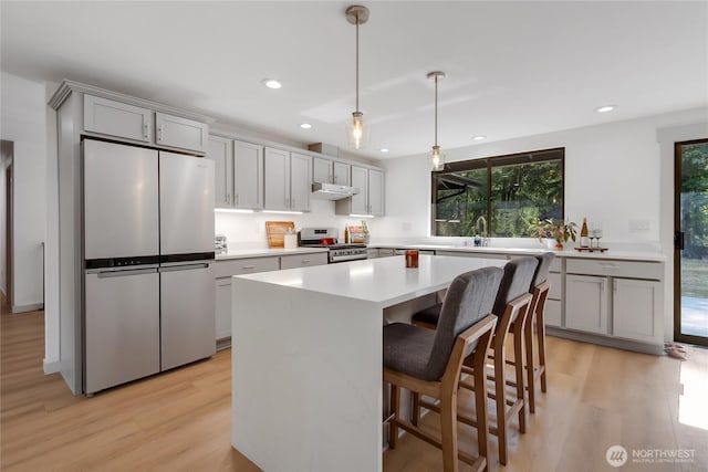 3327 170th Ave E, Lake Tapps, WA 98391 - kitchen with appliances with stainless steel finishes, light wood-style flooring, light countertops, a center island, and a kitchen bar