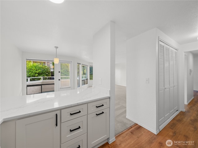 1113 5th Ave S Unit 107, Edmonds, WA 98020 - kitchen with light wood-style flooring, white cabinetry, light stone counters, and decorative light fixtures