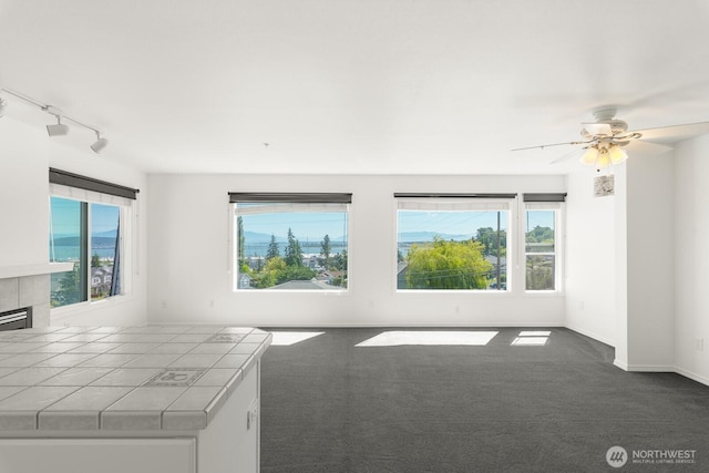 910 34th St Unit 302, Anacortes, WA 98221 - unfurnished living room with dark colored carpet, a ceiling fan, and rail lighting