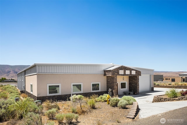 431 Airport Way SW, Mattawa, WA 99349 - view of front of home with a garage, stone siding, a mountain view, driveway, and stucco siding