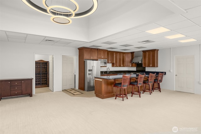 431 Airport Way SW, Mattawa, WA 99349 - kitchen featuring high end refrigerator, a kitchen bar, wall chimney exhaust hood, light colored carpet, and a paneled ceiling