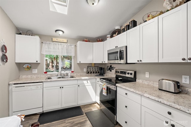 101 Shenandoah Dr, Silverlake, WA 98645 - kitchen featuring stainless steel appliances, white cabinetry, wood finished floors, and a skylight