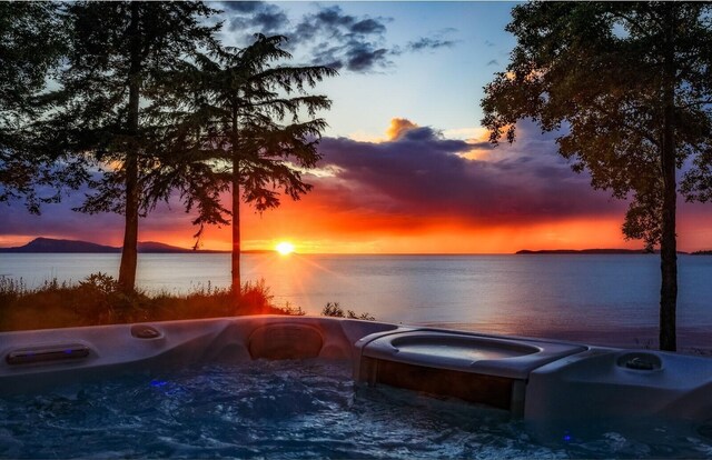 385 Sunset Ave, Orcas Island, WA 98245 - pool at dusk featuring a water view and an outdoor hot tub
