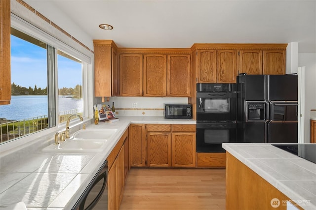 3604 Serene Way, Lynnwood, WA 98087 - kitchen with black appliances, light wood-style floors, brown cabinetry, and tile countertops