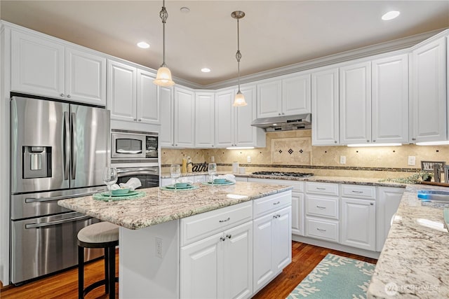 17445 NE 28th St, Redmond, WA 98052 - kitchen featuring appliances with stainless steel finishes, under cabinet range hood, a center island, dark wood-style floors, and white cabinetry
