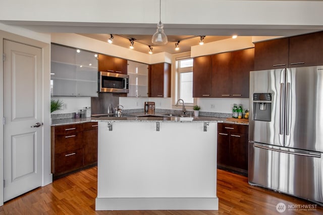 159 Denny Way Unit 603, Seattle, WA 98109 - kitchen with appliances with stainless steel finishes, a sink, wood finished floors, and a kitchen breakfast bar